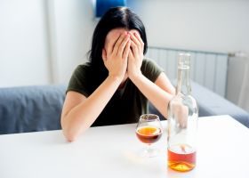woman sitting at table contemplating drinking alcohol - Alcohol Addiction Help concept image